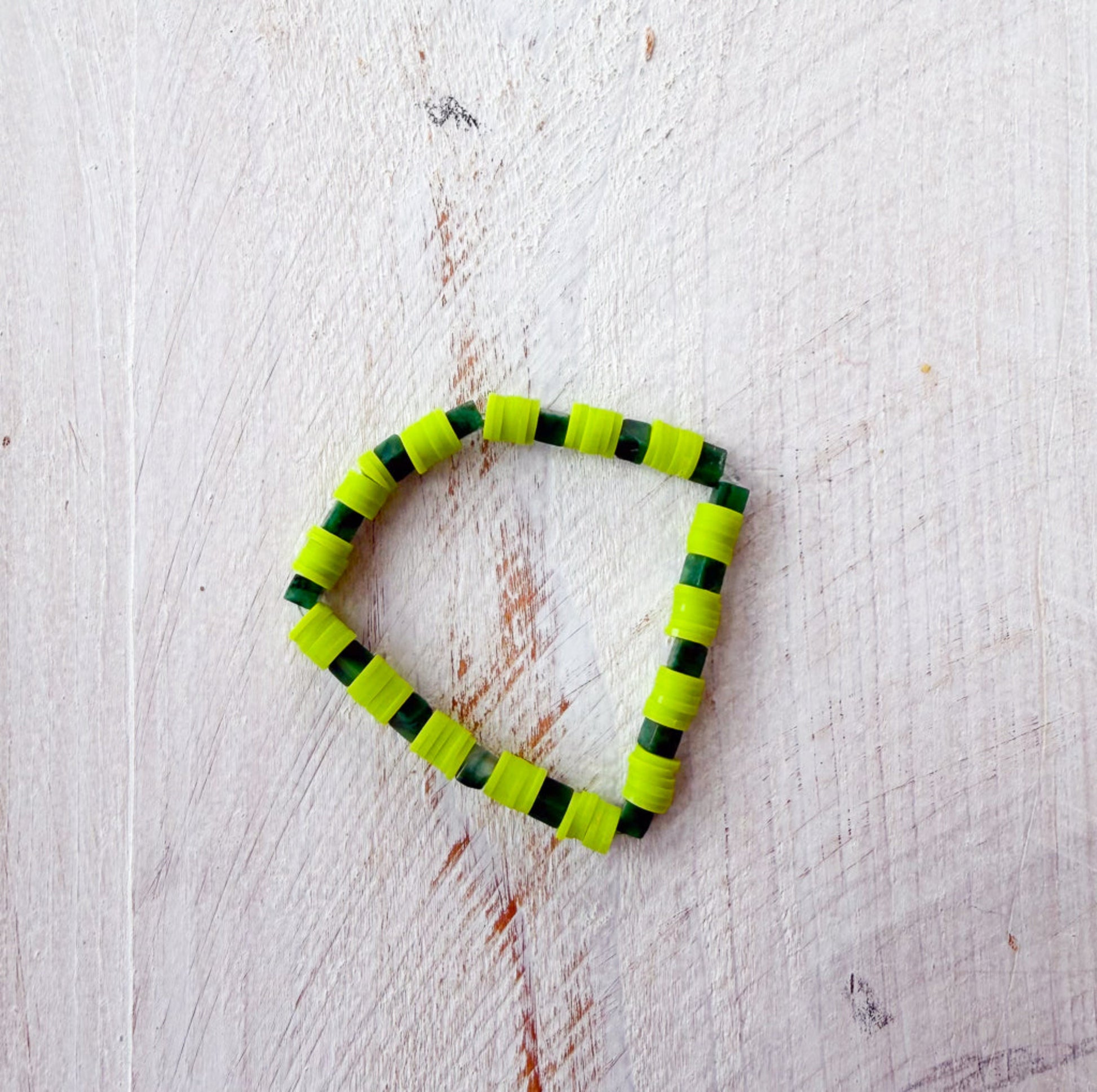 Green and black beaded bracelet on a light wooden surface