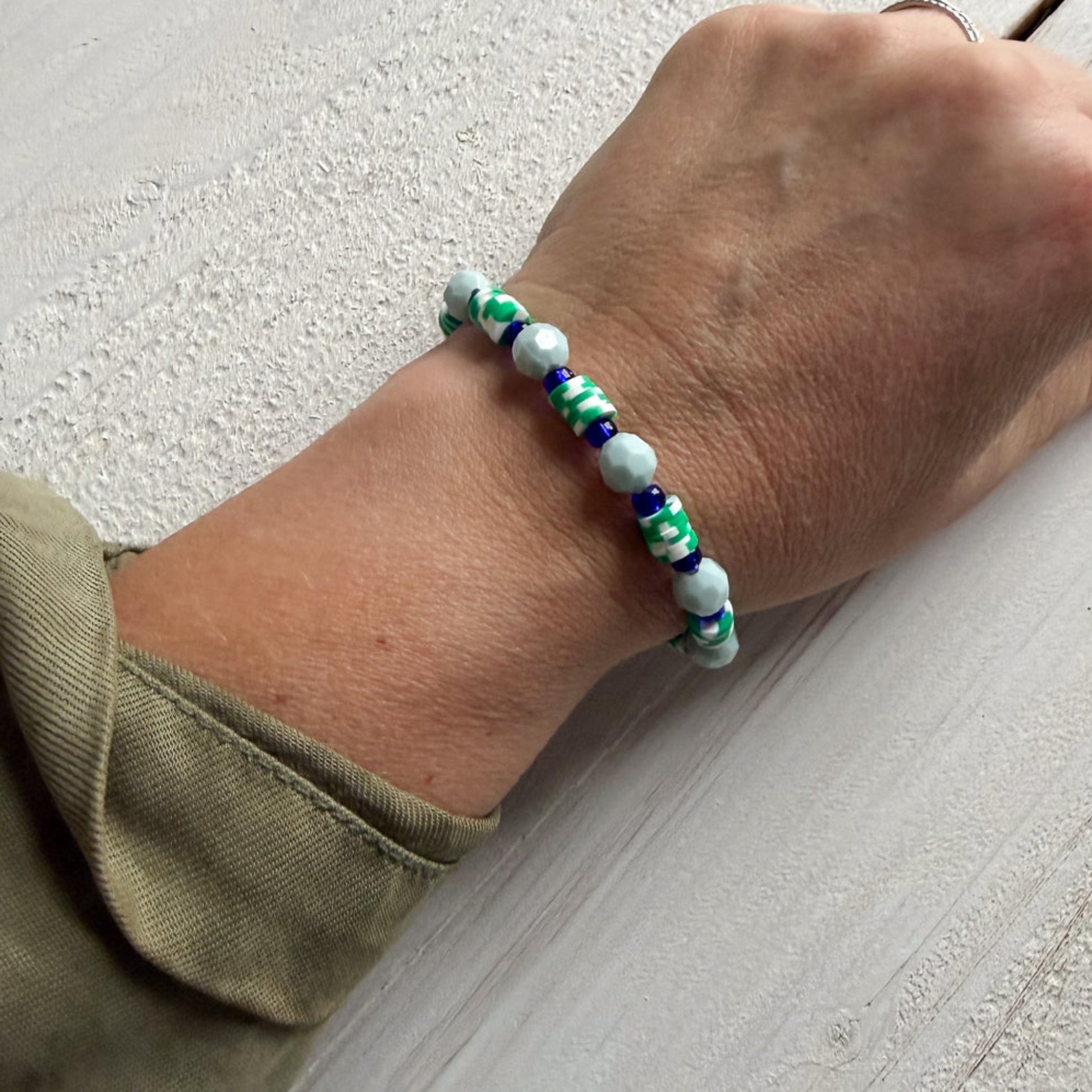 Hand wearing a beaded bracelet on a light surface