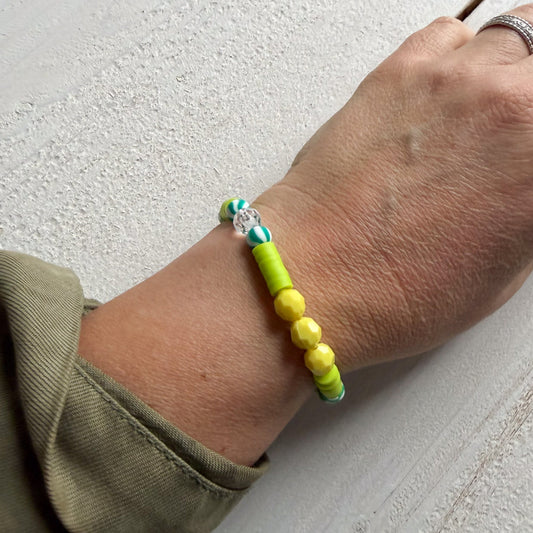Hand wearing a bracelet with green beads on a light gray background