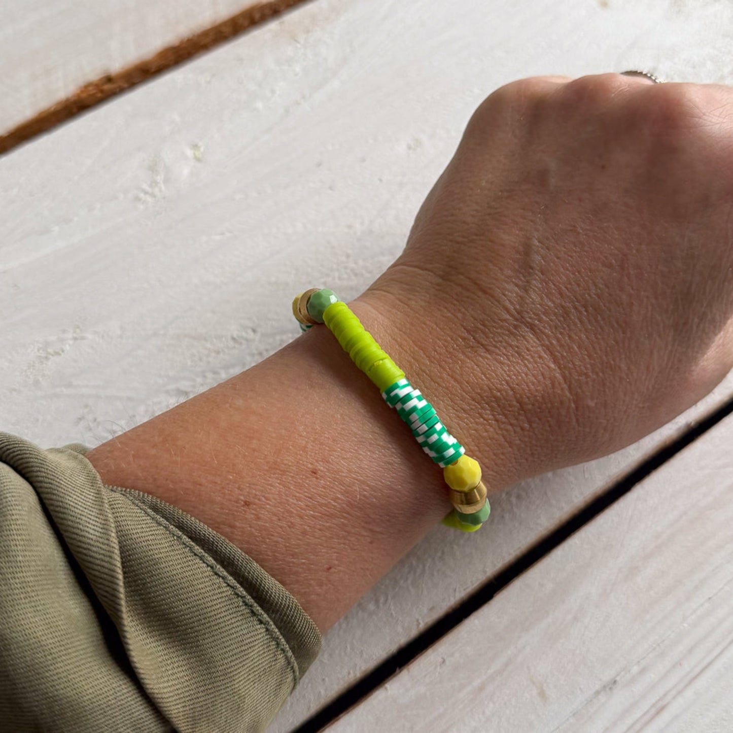 Hand wearing a colorful bracelet on a light wooden surface