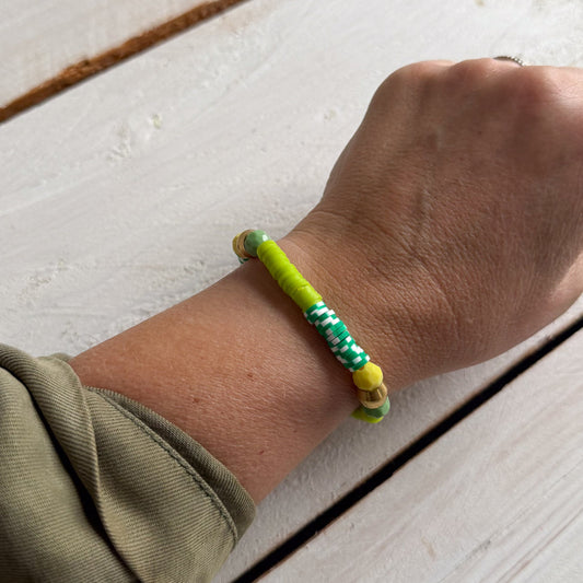 Hand wearing a colorful bracelet on a light wooden surface