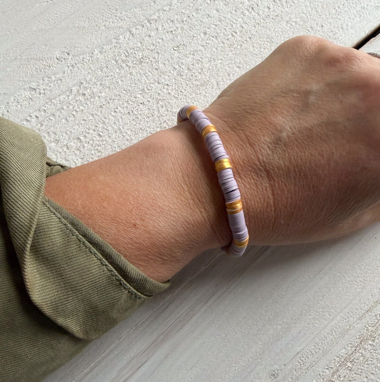 Hand wearing a bracelet on a textured surface